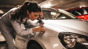Mulher inspecionando arranhão no carro